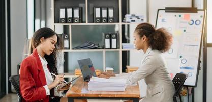 Geschäftsfrauen arbeiten und diskutieren ihre Geschäftspläne. eine menschliche mitarbeiterin erklärt und zeigt ihrer kollegin das ergebnispapier im modernen büro. foto