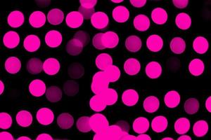Unfokussiertes abstraktes rosa Bokeh auf schwarzem Hintergrund. defokussiert und verschwommen viele runde licht foto