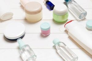 Nahaufnahme von Kosmetikflaschen, Gläsern, Behältern und Sprays auf weißem Holzhintergrund. Schönheitskonzept mit Kopienraum foto