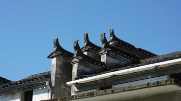 die schöne traditionelle chinesische dorfansicht mit der klassischen architektur und den frischen grünen bäumen als hintergrund foto