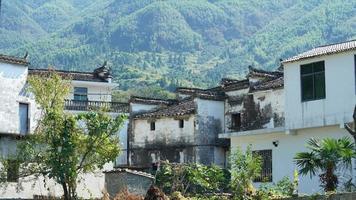 die schöne traditionelle chinesische dorfansicht mit der klassischen architektur und den frischen grünen bäumen als hintergrund foto