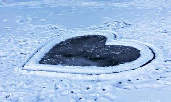 großes Herz auf einem zugefrorenen See mit Schnee bedeckt. eisiges herz, valentinstag und romantisches konzept, kopierraum foto