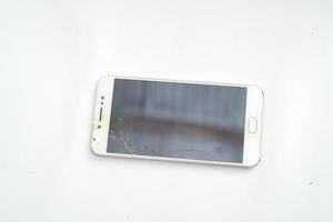 Flaches Smartphone mit kaputtem Bildschirm auf weißem Hintergrund foto