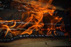 Holz brennende, verkohlte Bretter aus Holzstämmen in einem Feuer mit Feuerzungen und Rauch. Textur, Hintergrund foto