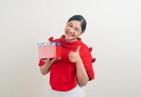 glückliche asiatische frau, die rotes hemd mit geschenkbox auf hand für weihnachtsfest trägt foto