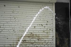 Wasserstrahl und schmutzige Wand. Schmutz vom Gebäude waschen. Strahl unter Druck. foto