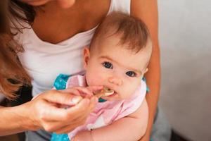 Mutter füttert niedliches Babymädchen Gemüsepüree aus einem Löffel. Gesunde Ernährung für kleine Kinder foto