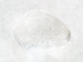 getrommelter Bergkristall-Edelstein auf weißem Marmor foto