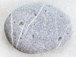 getrommelter Grauwacke-Sandstein auf weißem Marmor foto