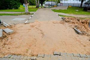 demontierter Straßenbelag aus Zementbetonfliesen, Ziegeln. unfertige Straße foto