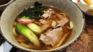 Nahaufnahme von Udon-Nudeln mit Suppe, geschnittenem Schweinefleisch, Algen oder Algen, japanische Frühlingszwiebeln auf Schüssel im japanischen Restaurant. warmes oder asiatisches Essen. foto