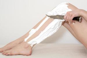 Beine einer Frau, die sich mit einem Messer rasiert foto
