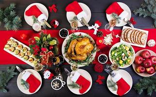 gebackener Truthahn. Weihnachtsessen. Der Weihnachtstisch wird mit einem Truthahn serviert, der mit leuchtendem Lametta und Kerzen dekoriert ist. Brathähnchen, Tisch. Familienessen. Ansicht von oben foto
