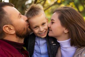 mama und papa küssen einen kleinen jungen zwischen sich, nahaufnahmeporträt foto