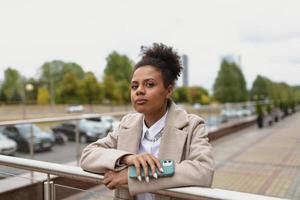 Porträt einer ernsthaften afroamerikanischen Frau mit einem Handy im Hintergrund der Stadt foto