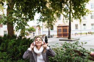 eine erwachsene frau mit kopfhörern wird high von der musik im hintergrund des stadtplatzes foto