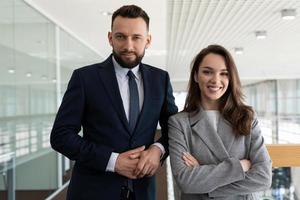 heterosexuelle unternehmensleiter in geschäftsanzügen vor dem hintergrund eines modernen, stilvollen büros, konzept von bankdienstleistungen foto