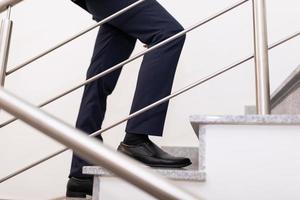 Nahaufnahme der Beine eines Geschäftsmannes, der die Treppe hinaufsteigt, das Konzept eines erfolgreichen Geschäfts- und Karrierewachstums foto