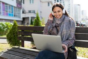 junge frau im videochat mit laptop und kopfhörer mit einem lächeln im gesicht, dem konzept der fernarbeit foto