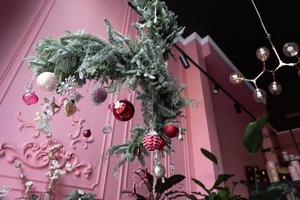 Komposition aus natürlichen Tannennadeln, die von der Decke hängen, mit Weihnachtsschmuck im Inneren eines Blumenladens foto