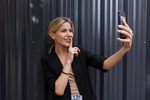 Frau mittleren Alters im Büro, die Geheimnisse per Videoanruf auf dem Hintergrund einer grauen Wand macht foto