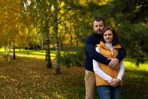 glückliche klassische traditionelle familie, die gegen herbstwaldhintergrund umarmt foto