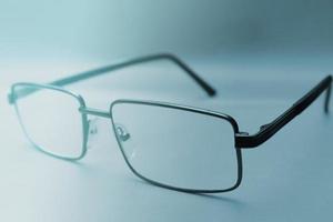Brille in einem schwarzen Rahmen auf blauem Hintergrund mit Kopierraum. Welttag des Sehens. Fokus im Vordergrund. unscharfer Hintergrund foto