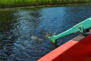 hölzerne ruder für das boot, das auf einem ruhespaziergang auf dem wasser des sees, des flusses, des meeres auf die natur ins wasser gesenkt wird foto