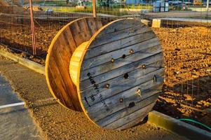 große Holzspule zum Aufwickeln von Hochspannungsdraht oder -kabel. gelbe und glatte Holzspule, Drahtwicklung. Werkzeug für Strom. mit Löchern um den Umfang, aus glatten Brettern foto