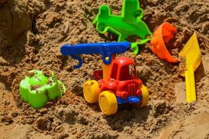 Kindersandkasten auf dem Spielplatz zum Spielen mit Spielzeug für Kinder per LKW, Auto, Bagger, Sandstreuer mit Spachtel foto