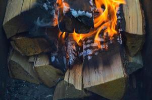 Holz brennende, verkohlte Bretter aus Holzstämmen in einem Feuer mit Feuerzungen und Rauch. Textur, Hintergrund foto