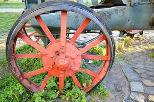 altes rotes Eisenrad verschmolzen mit dem Gras foto