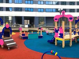 rosa Kinderspielplatz im Zentrum der Wohnanlage. Für Kinder gibt es Schaukeln, Rechenbrett, lustige Rutschen und Klettergerüste. Spielplatz in einem neuen Gebiet neben hohen Wohnhäusern foto