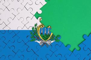 Die Flagge von San Marino ist auf einem fertigen Puzzle mit freiem Platz für grüne Kopien auf der rechten Seite abgebildet foto