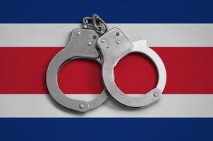 costa rica flagge und polizeihandschellen. das Konzept der Einhaltung des Gesetzes im Land und des Schutzes vor Kriminalität foto