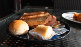 Scheiben Brot, Brötchen, Marmeladenbrötchen und Butter zum Frühstück foto