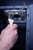 Reinigung eines schmutzigen Computerlüfters mit einer Bürste foto