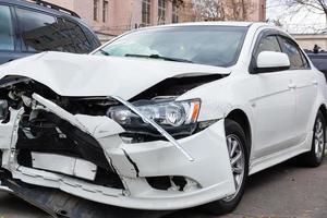 Die Vorderseite des weißen Autos wird durch einen Unfall auf der Straße beschädigt foto