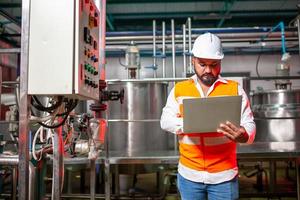 professionelle ingenieure mit helmen arbeiten an der wartung von industriebaugeräten, arbeiter inspizieren oder reparieren maschinen mit laptop. foto