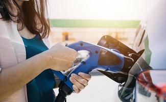 hand, die ein ladegerät in eine elektroautosteckdose einsteckt. elektroauto oder ev wird an der station aufgeladen foto