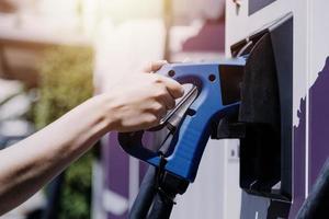 hand, die ein ladegerät in eine elektroautosteckdose einsteckt. elektroauto oder ev wird an der station aufgeladen foto