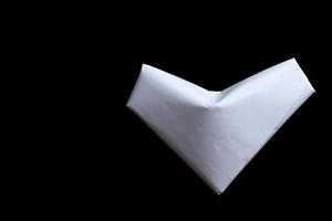 weißes Papier gefaltetes Origami-Liebesherz lokalisiert auf schwarzem Hintergrund. foto