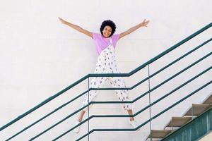 Fröhliche schwarze Frau, die auf der Treppe springt foto