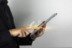 Der Finger eines intelligenten Mannes, der auf ein Gerät mit Touchscreen-Technologie zeigt, und ein Geschäftsmann, der auf dem iPad-Bildschirm berührt foto