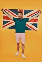 in voller Länge von einem hübschen jungen Mann in Freizeitkleidung mit britischer Flagge foto