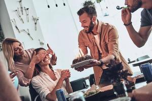 unser Geburtstagskind. gruppe glücklicher leute, die geburtstag unter freunden feiern und lächeln, während sie eine party genießen foto