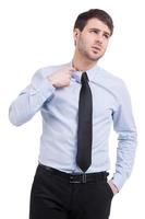 Unsicherheit. frustrierter junger mann in hemd und krawatte, der hand an den haaren hält, während er isoliert auf weiß steht foto
