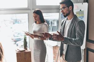 Geschäftsideen teilen. Zwei junge Kollegen führen eine Präsentation durch, während sie mit ihrem Geschäftsteam im Büro arbeiten foto