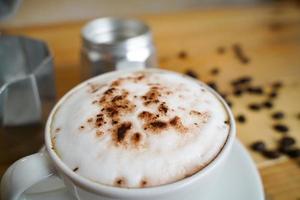 Heißer Cappuccino in weißer Tasse mit Holzhintergrund, Kaffee ist ein beliebtes Getränk auf der ganzen Welt. foto