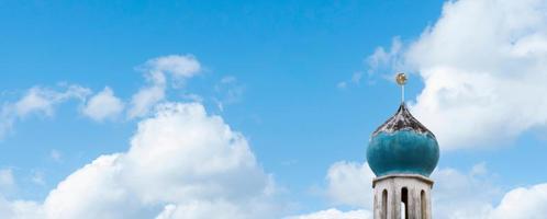 Halbmond und Stern an der Spitze der alten Moschee über den Wolken auf blauem Himmelshintergrund. die moschee ist wichtig für die islamische religion, eid al-adha, eid mubarak, eid al fitr, ramadan kareem foto